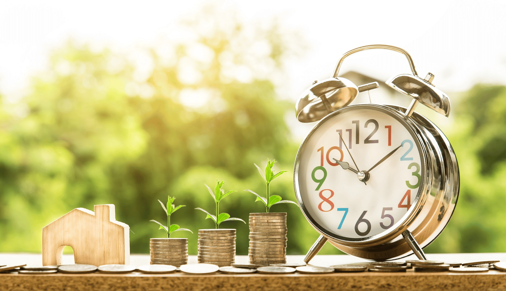 Clock and stacks of coins with nature as background